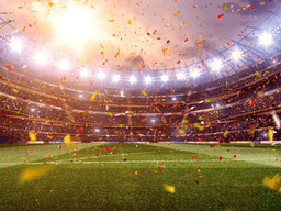 FIFA World Cup trophy beside a soccer ball on a grass field.